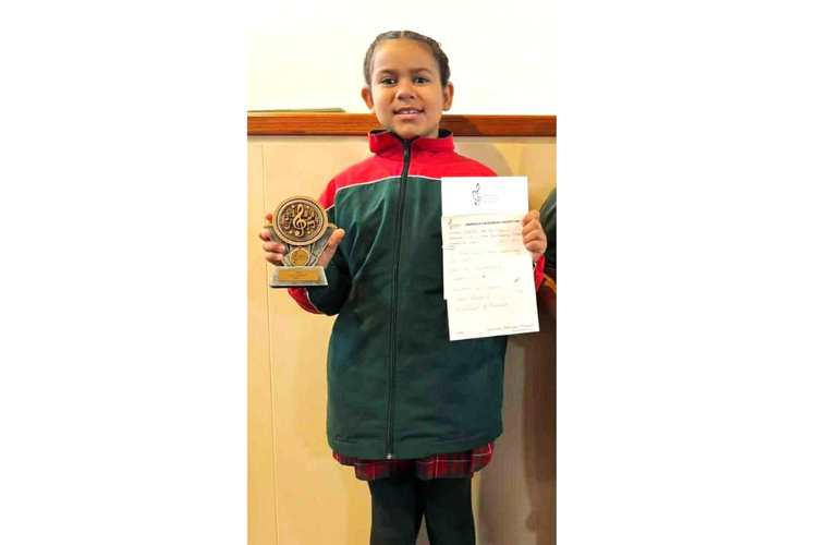 A 3/4 student holding the award their class won coming first in the Eisteddfod.