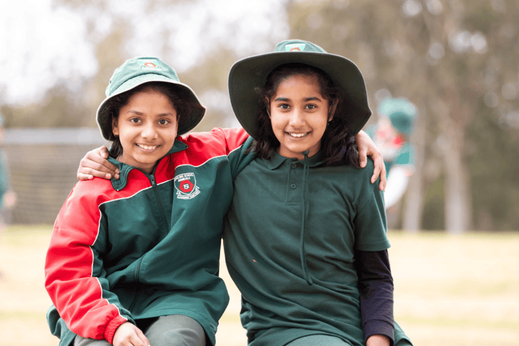 Two of our international students sitting happily together in the playground.